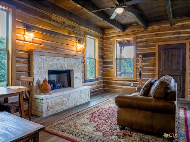 living room with a fireplace, rustic walls, wood ceiling, hardwood / wood-style flooring, and beamed ceiling