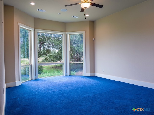 empty room featuring ceiling fan and dark carpet