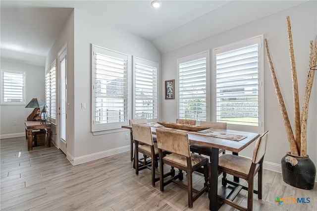 dining space featuring vaulted ceiling, a wealth of natural light, and light hardwood / wood-style flooring