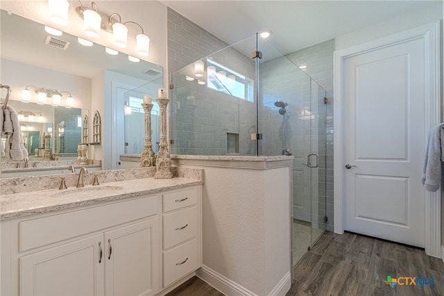 bathroom featuring walk in shower, vanity, and hardwood / wood-style flooring