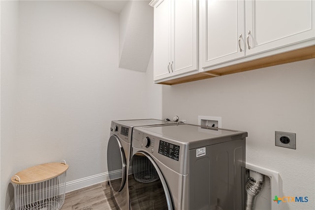 washroom with washing machine and dryer, cabinets, and light hardwood / wood-style floors