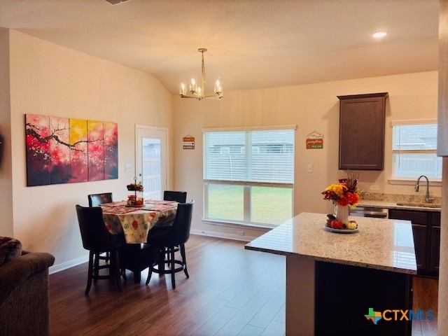 dining room featuring sink, dark wood-type flooring, lofted ceiling, and an inviting chandelier