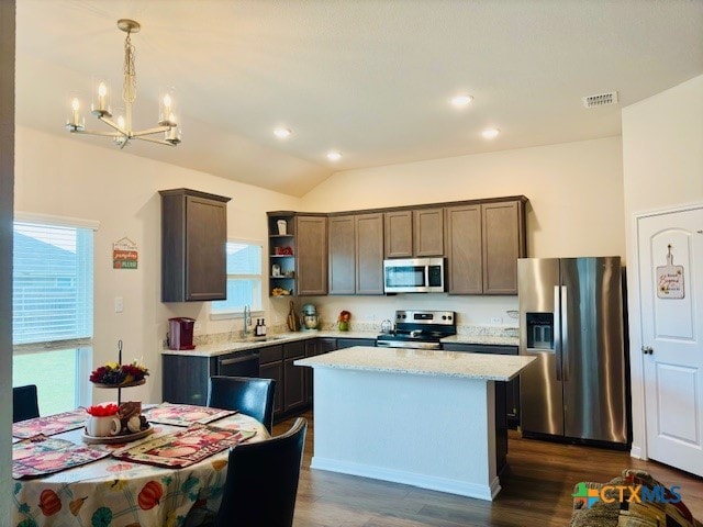 kitchen with a center island, dark hardwood / wood-style flooring, lofted ceiling, decorative light fixtures, and appliances with stainless steel finishes