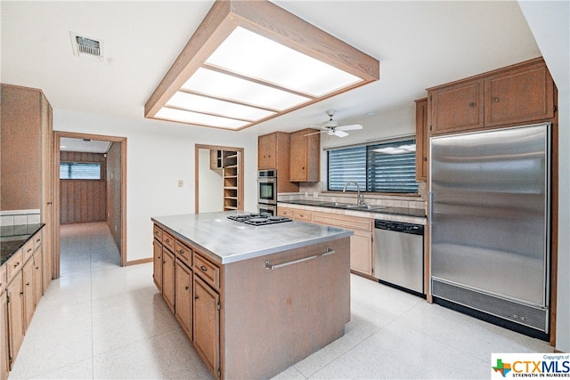 kitchen featuring backsplash, stainless steel appliances, ceiling fan, sink, and a kitchen island