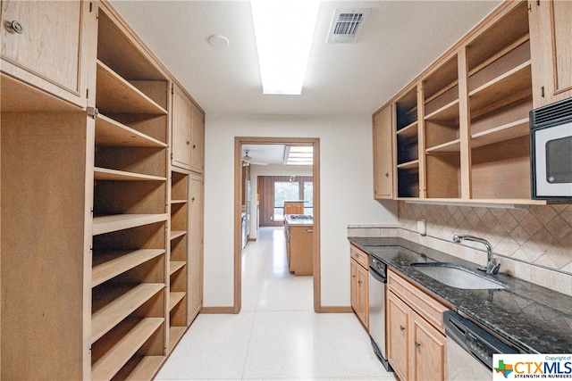 kitchen with light brown cabinetry, backsplash, dark stone counters, and sink