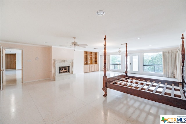 unfurnished living room with built in shelves, ceiling fan, crown molding, and a high end fireplace