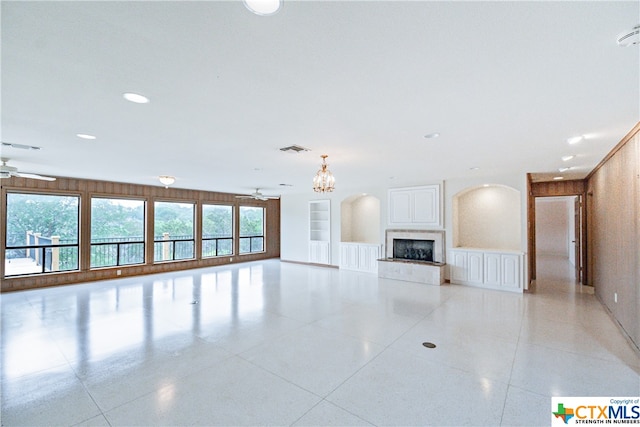 unfurnished living room featuring ceiling fan, built in features, and light tile patterned floors