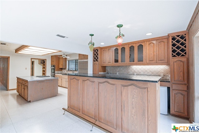 kitchen with a center island, stainless steel appliances, kitchen peninsula, decorative light fixtures, and decorative backsplash