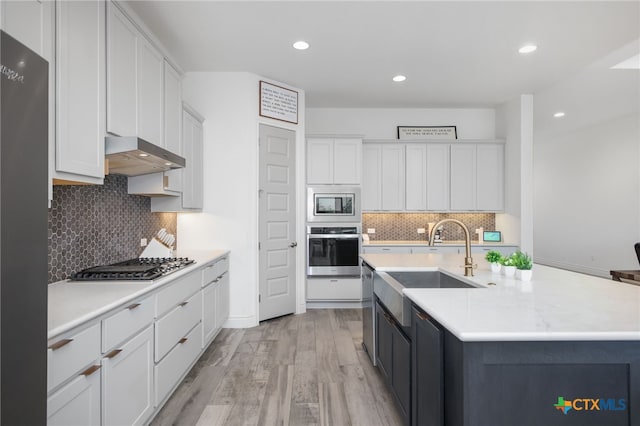 1386 Lyme Park, Bulverde, TX 78163 - kitchen featuring stainless steel appliances, range hood, light countertops, light wood-style flooring, and tasteful backsplash