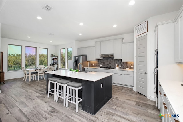 1386 Lyme Park, Bulverde, TX 78163 - kitchen with a center island with sink, stainless steel appliances, backsplash, light countertops, and a kitchen breakfast bar