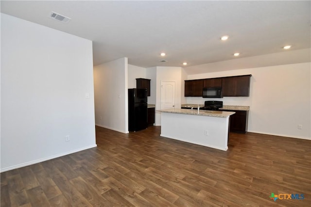 kitchen featuring a kitchen island with sink, dark wood-type flooring, light stone counters, black appliances, and dark brown cabinets