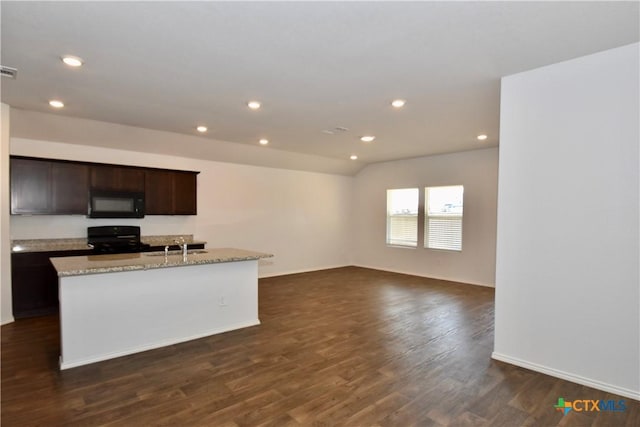 kitchen with stove, a kitchen island with sink, light stone counters, and dark hardwood / wood-style flooring