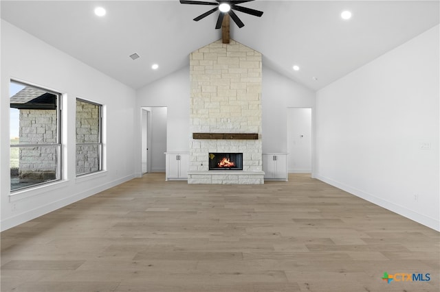 unfurnished living room with ceiling fan, a stone fireplace, light hardwood / wood-style flooring, and high vaulted ceiling