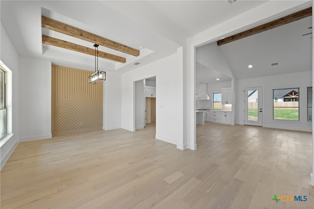 unfurnished living room with an inviting chandelier, light wood-type flooring, and lofted ceiling with beams