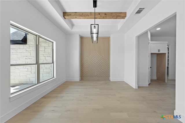 unfurnished dining area with light wood-type flooring, a raised ceiling, and beamed ceiling