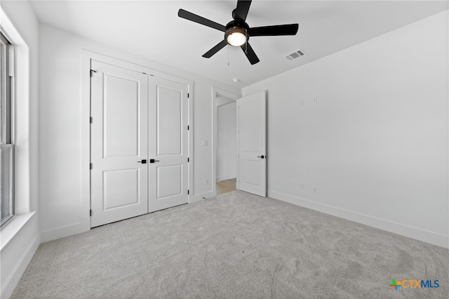 unfurnished bedroom with ceiling fan, a closet, and light colored carpet