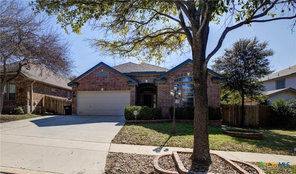 view of front facade featuring driveway, brick siding, an attached garage, and fence