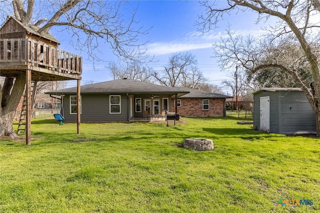 back of house with a wooden deck, a storage unit, a lawn, and an outdoor fire pit