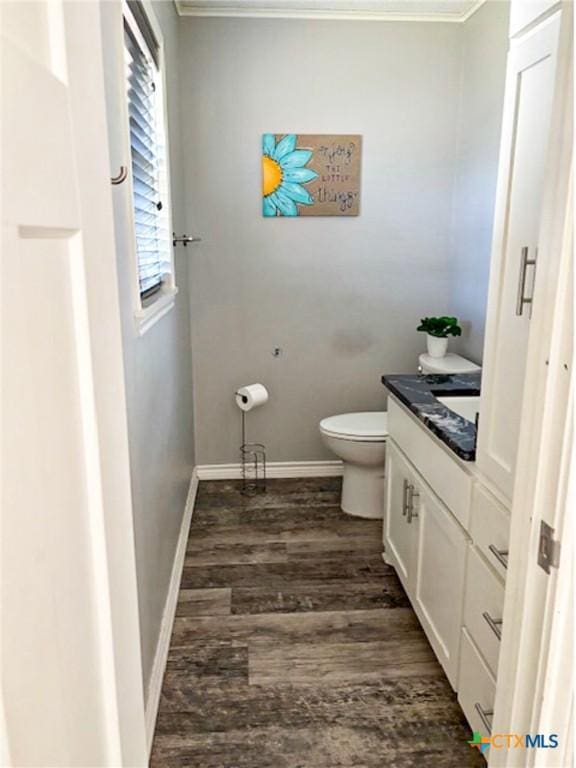 bathroom featuring hardwood / wood-style flooring, ornamental molding, vanity, and toilet