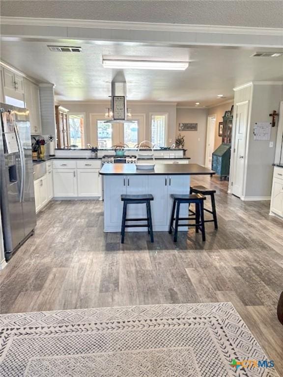 kitchen featuring white cabinetry, a center island, stainless steel fridge, and a kitchen breakfast bar