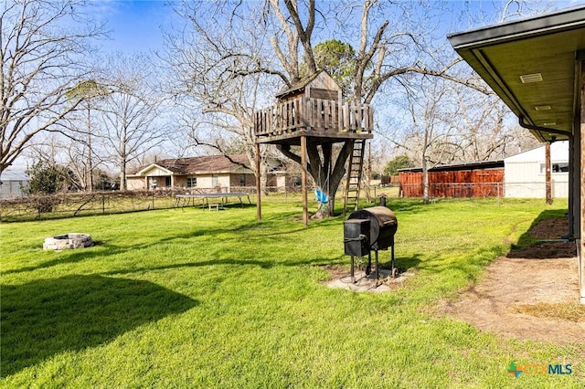 view of yard featuring a trampoline and an outdoor fire pit