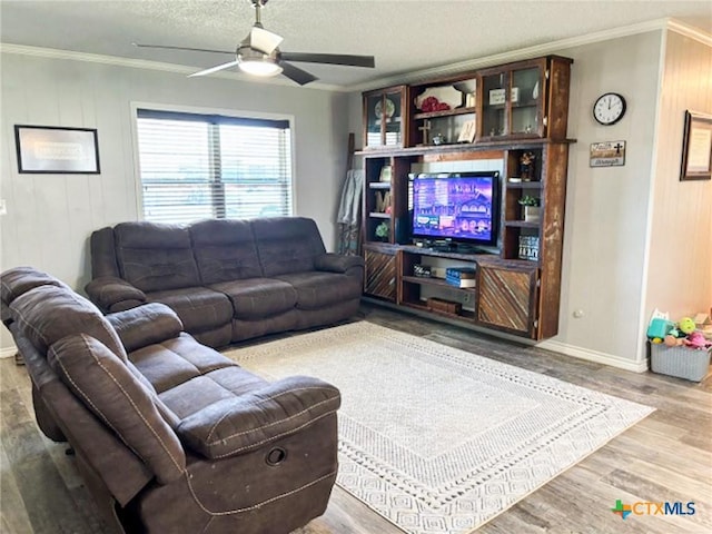 living room with ceiling fan, light hardwood / wood-style flooring, ornamental molding, and a textured ceiling