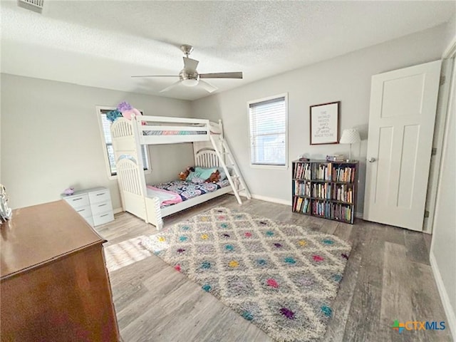 bedroom with ceiling fan, hardwood / wood-style floors, and a textured ceiling