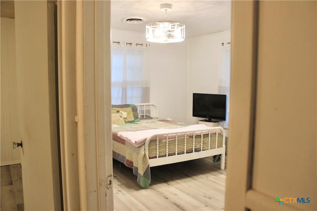 bedroom with light hardwood / wood-style floors and an inviting chandelier