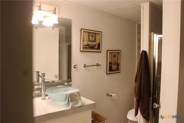 bathroom with toilet, a drop ceiling, and sink