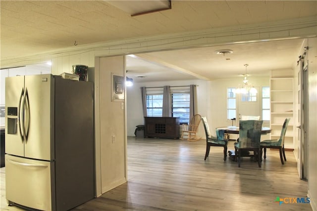 dining space with a barn door, wood-type flooring, crown molding, and an inviting chandelier