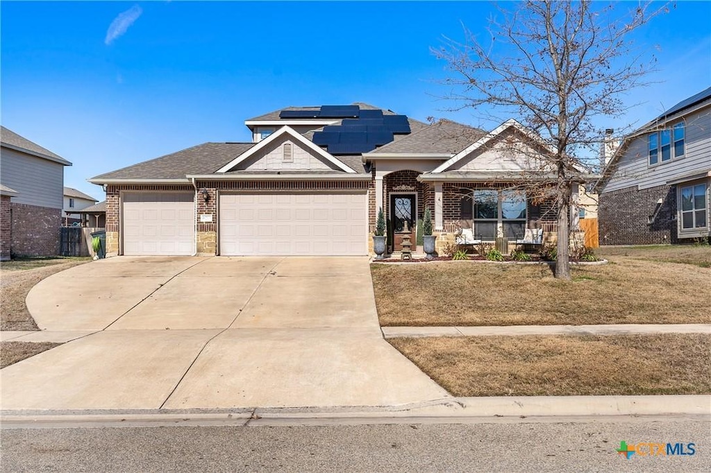 craftsman house with a garage, a porch, a front lawn, and solar panels