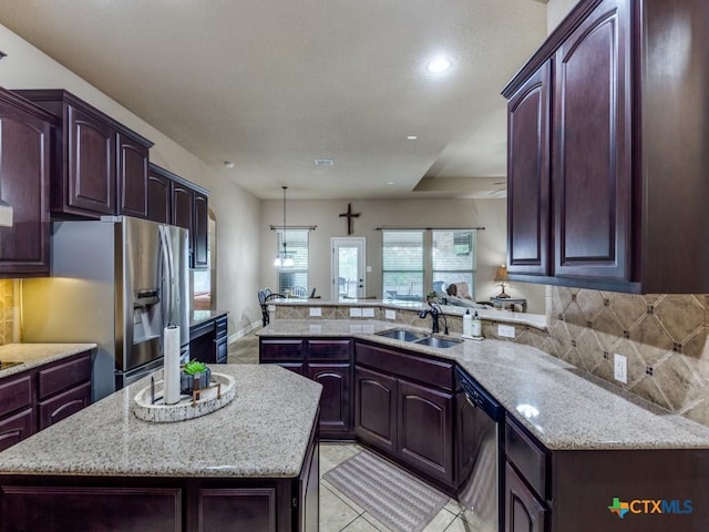 kitchen featuring kitchen peninsula, appliances with stainless steel finishes, sink, and a kitchen island