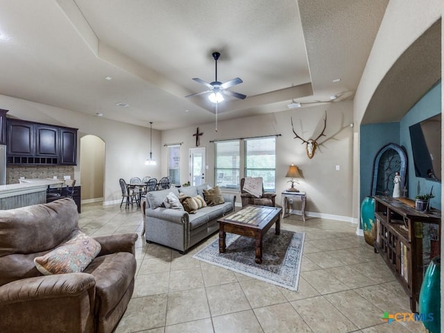 living room with ceiling fan, light tile patterned floors, and a tray ceiling