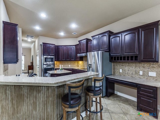 kitchen featuring tasteful backsplash, a breakfast bar, kitchen peninsula, and stainless steel appliances