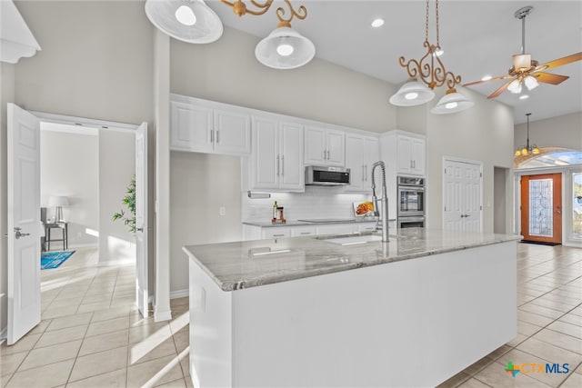 kitchen with white cabinetry, stainless steel appliances, light tile patterned floors, and a large island