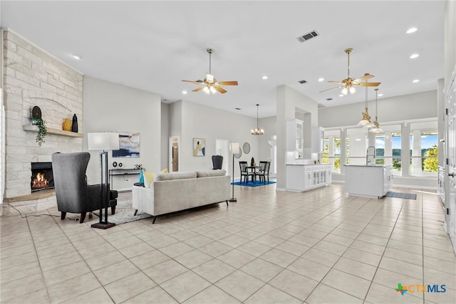 tiled living room with a high ceiling, ceiling fan, and a fireplace