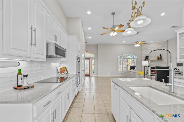 kitchen featuring stainless steel appliances, light tile patterned floors, sink, white cabinetry, and a fireplace