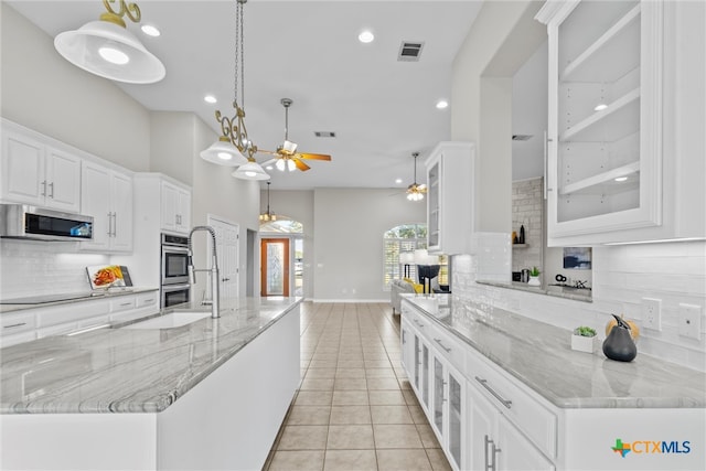 kitchen with a spacious island, light tile patterned floors, white cabinetry, appliances with stainless steel finishes, and decorative light fixtures