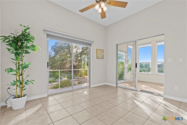 spare room with light tile patterned flooring, ceiling fan, and a healthy amount of sunlight