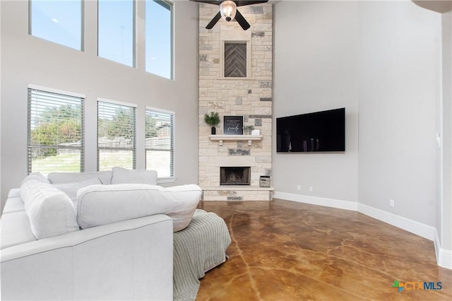 living room featuring ceiling fan, a fireplace, and a high ceiling