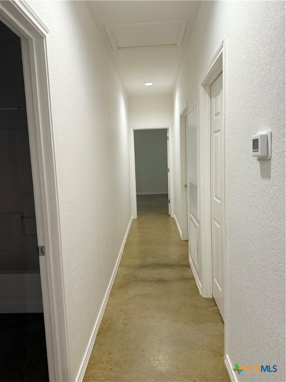 209 Anne Louise Dr, New Braunfels, TX 78130 - corridor with attic access, a textured wall, baseboards, and finished concrete floors