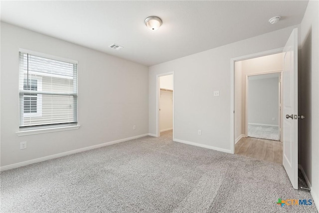 unfurnished bedroom with light colored carpet and a spacious closet