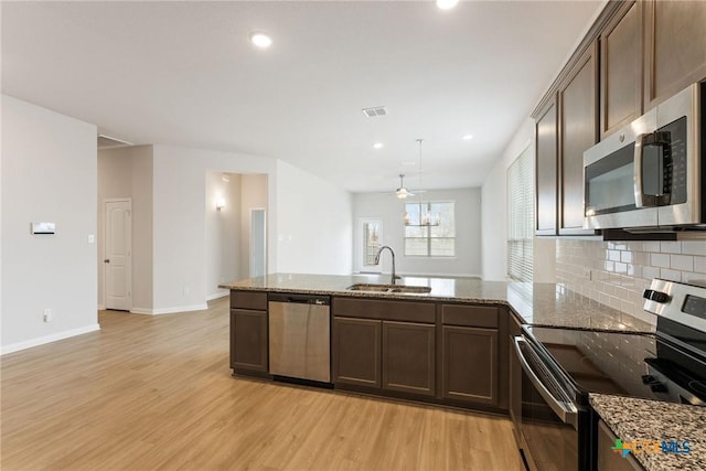 kitchen featuring light stone counters, sink, light hardwood / wood-style flooring, and appliances with stainless steel finishes