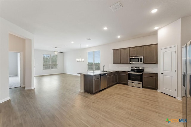 kitchen with pendant lighting, sink, appliances with stainless steel finishes, kitchen peninsula, and light wood-type flooring