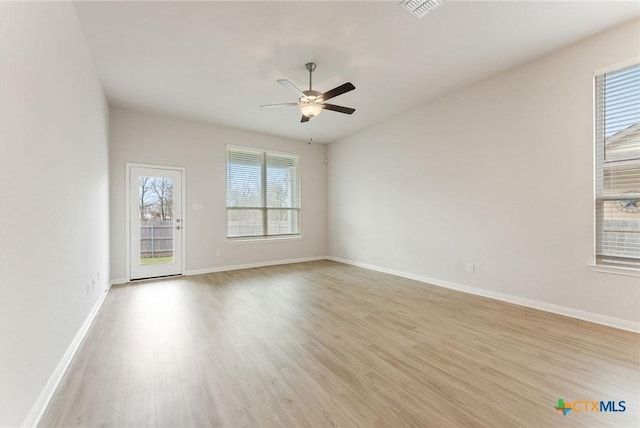 unfurnished room featuring ceiling fan, a wealth of natural light, and light wood-type flooring