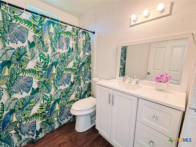 3007 Meadowlane St, Victoria, TX 77901 - full bathroom with wood finished floors, toilet, vanity, a shower with shower curtain, and a textured wall