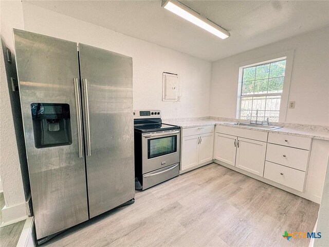3007 Meadowlane St, Victoria, TX 77901 - kitchen with stainless steel appliances, a sink, light wood-type flooring, white cabinets, and light stone counters