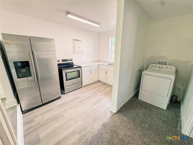 3007 Meadowlane St, Victoria, TX 77901 - kitchen with washer / dryer, appliances with stainless steel finishes, white cabinetry, light wood-style flooring, and light countertops