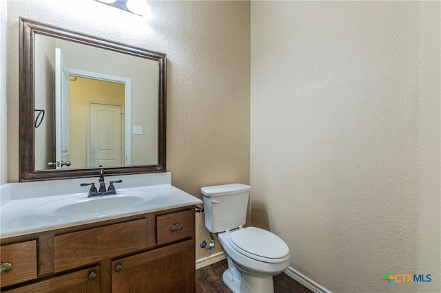 bathroom with wood-type flooring, vanity, and toilet