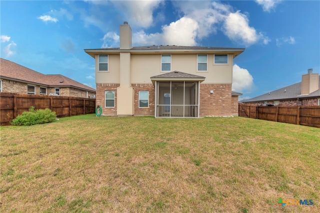 rear view of property with a sunroom and a yard